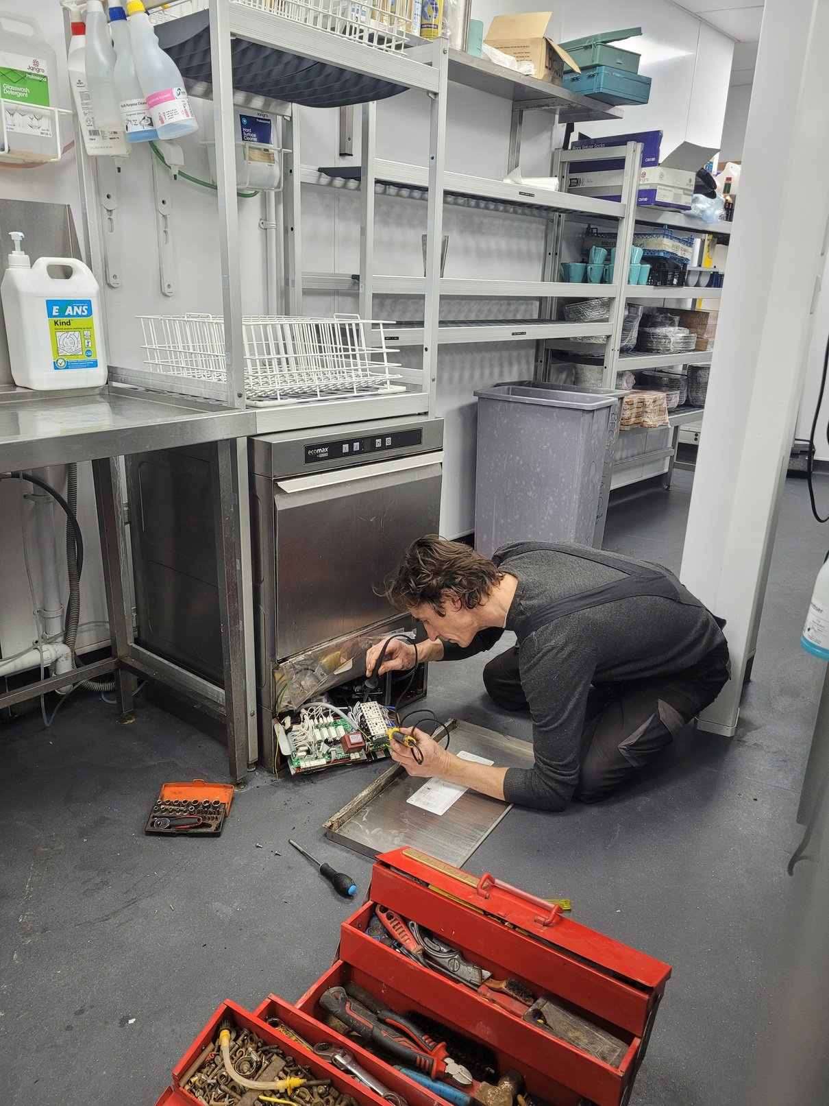 a person working on a dishwasher in a kitchen